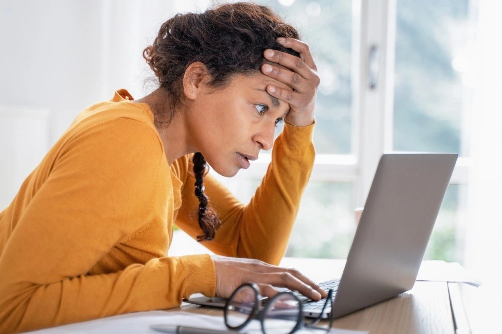 Mujer en computadora viendo si fue víctima de fraude cibernético.