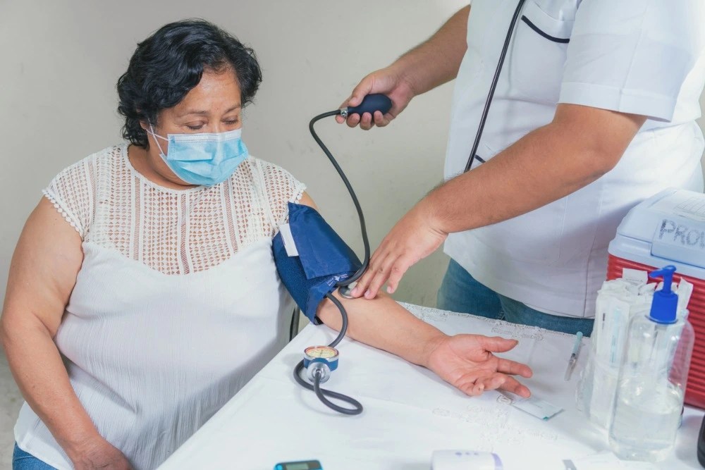 Enfermera tomando la presión de mujer que utiliza su seguro de gastos médicos