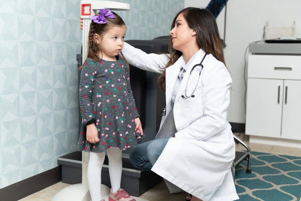 Doctora midiendo altura de una paciente pequeña