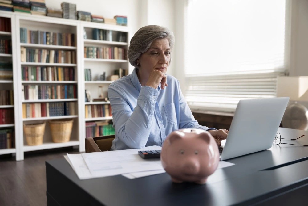 Adulta mayor revisando el estado de sus ahorros en su computadora.