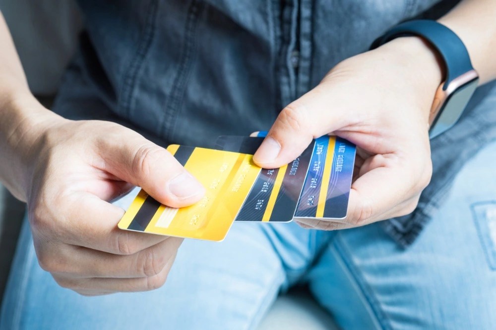 hombre con tres tarjetas bancarias en mano.