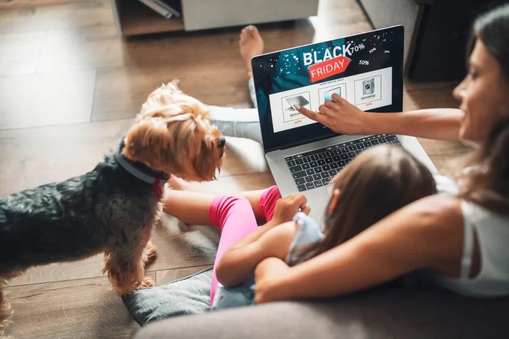 Mujer con hija y mascota al lado revisando los descuentos online