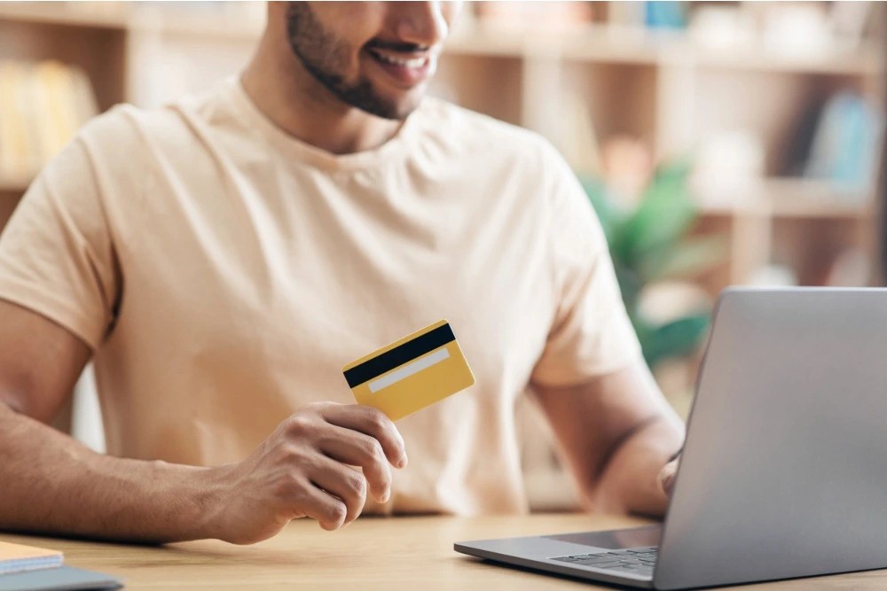 Hombre sosteniendo su tarjeta al hacer compras en línea.