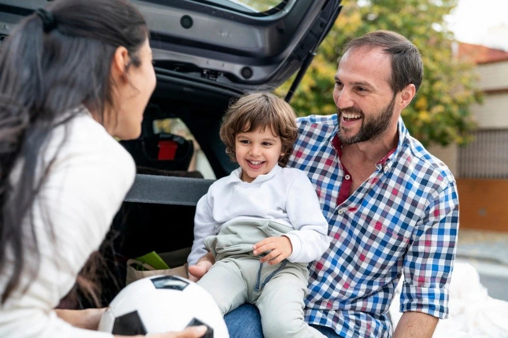 Familia feliz subiendo a su auto asegurado.