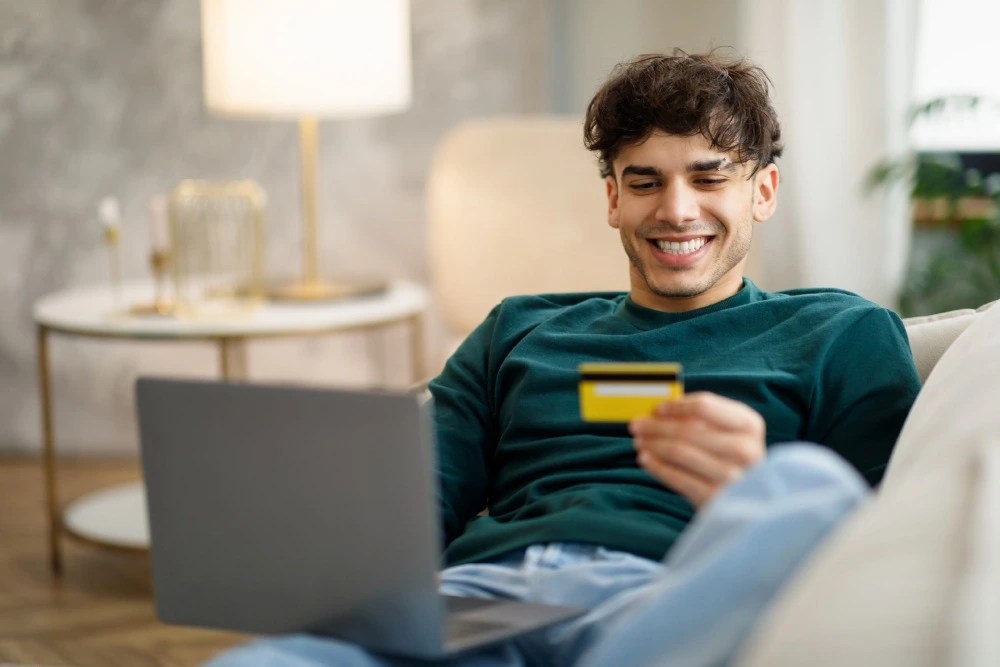 Joven comprando por internet con su tarjeta de crédito