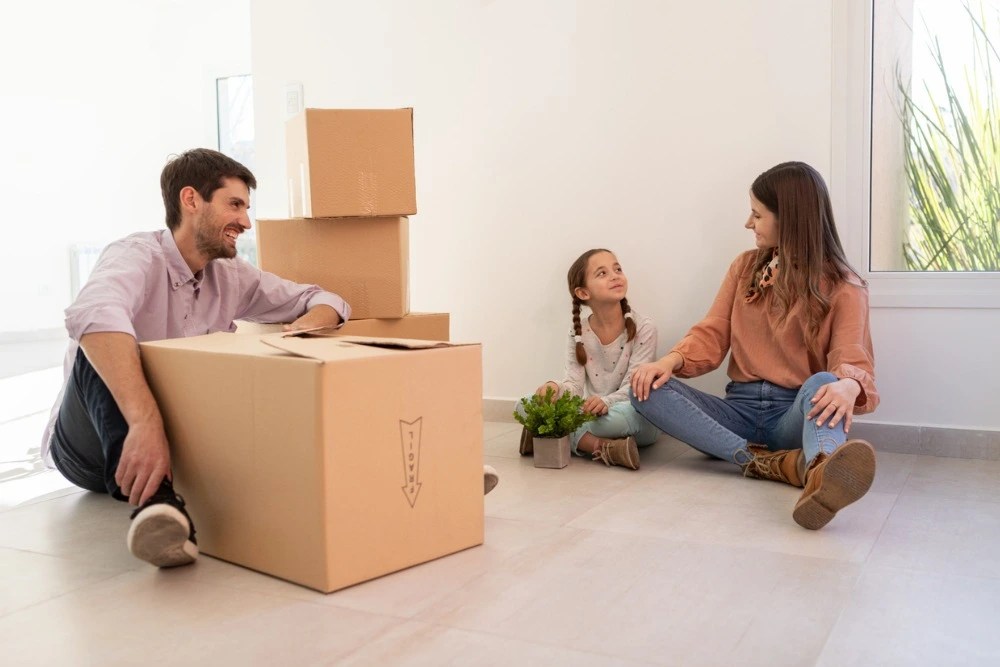 Familia en su nueva casa junto a cajas de mudanza.