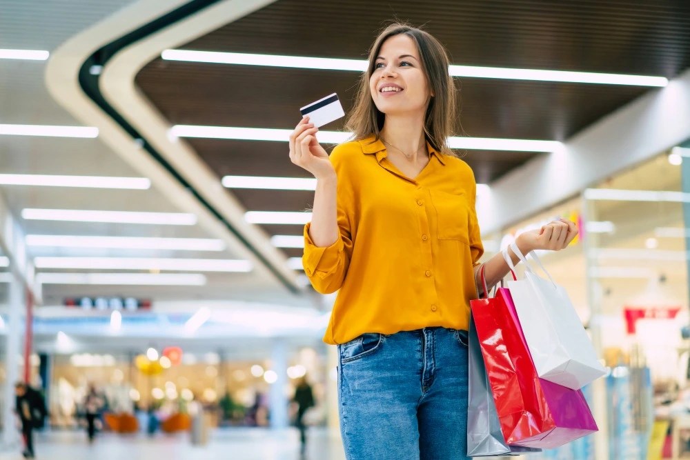 Mujer de compras en centro comercial con tarjeta de crédito.