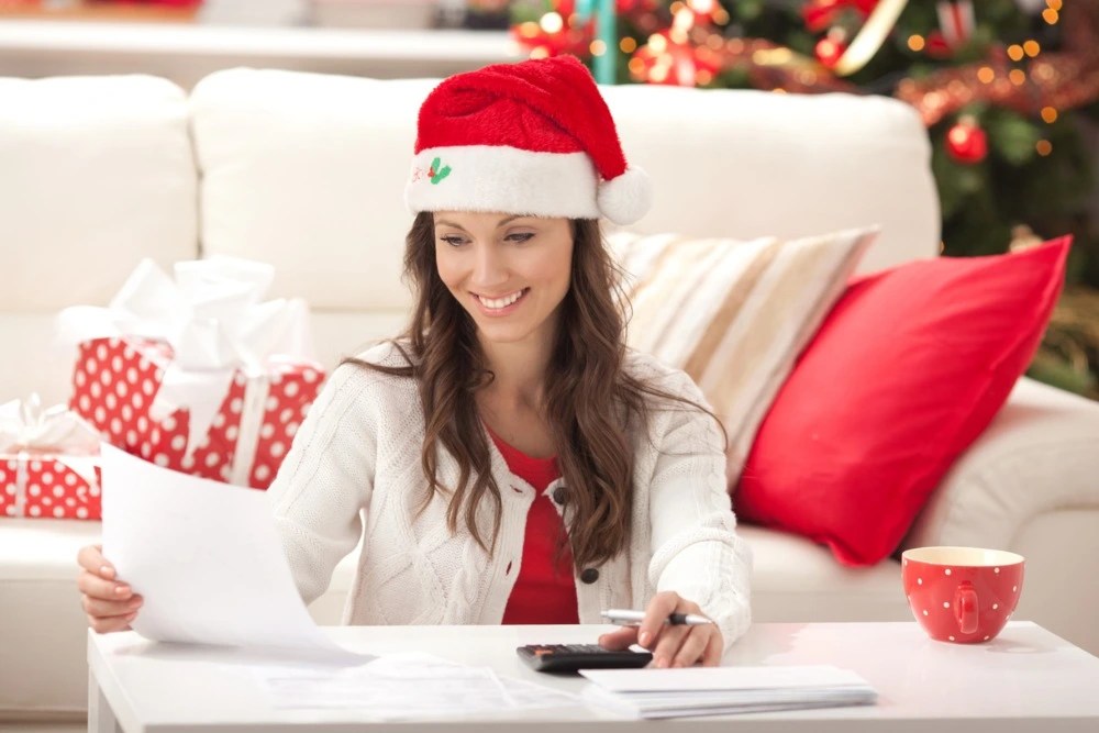 Mujer con gorro navideño haciendo un presupuesto de compras.