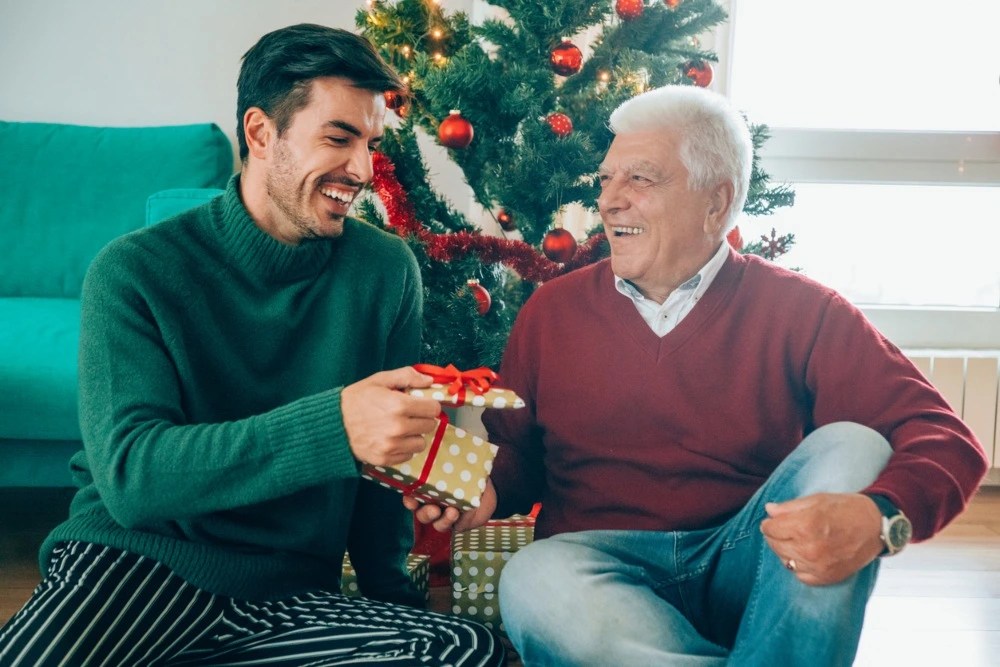 Abuelo y nieto compartiendo regalos navideños.