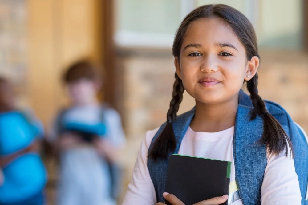 Seguro educativo: niña escolar con mochila y cuaderno