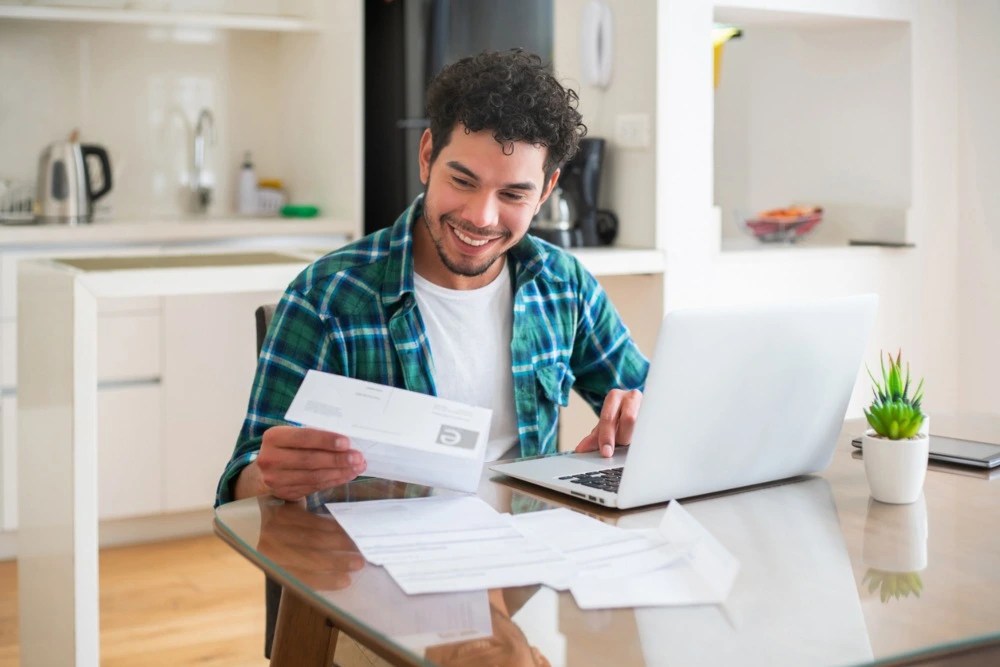 Hombre contento revisando su estado de cuenta tras aplicar consejos de cómo utilizar bien una tarjeta de crédito.