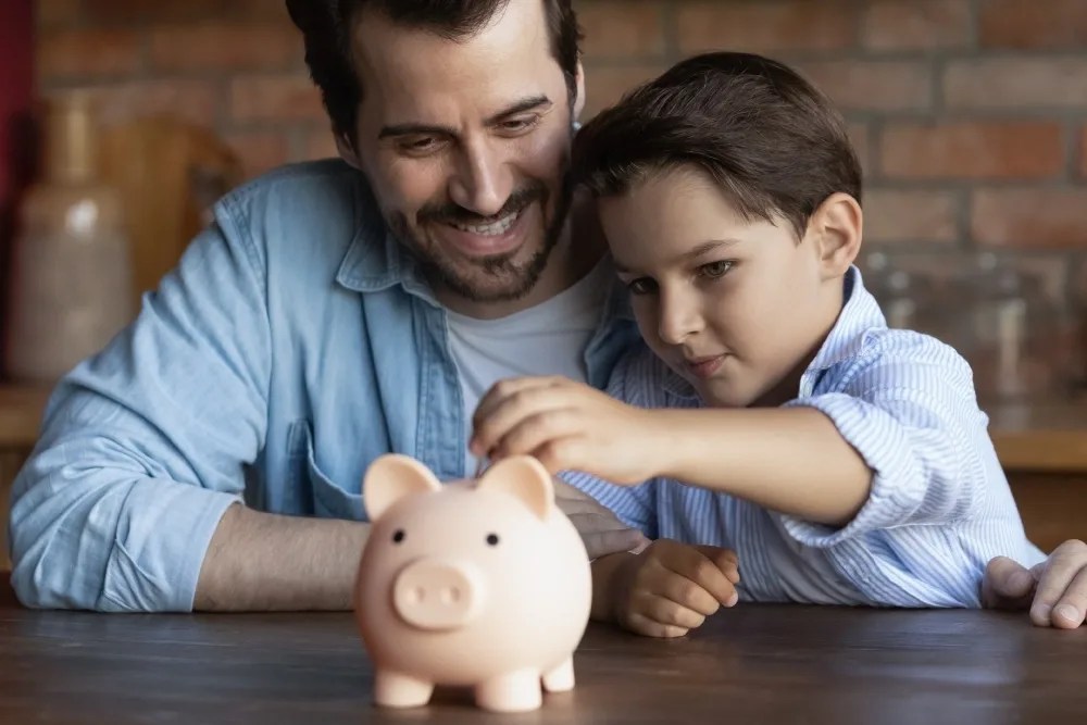 Padre e hijo ahorrando en una alcancia de cerdito