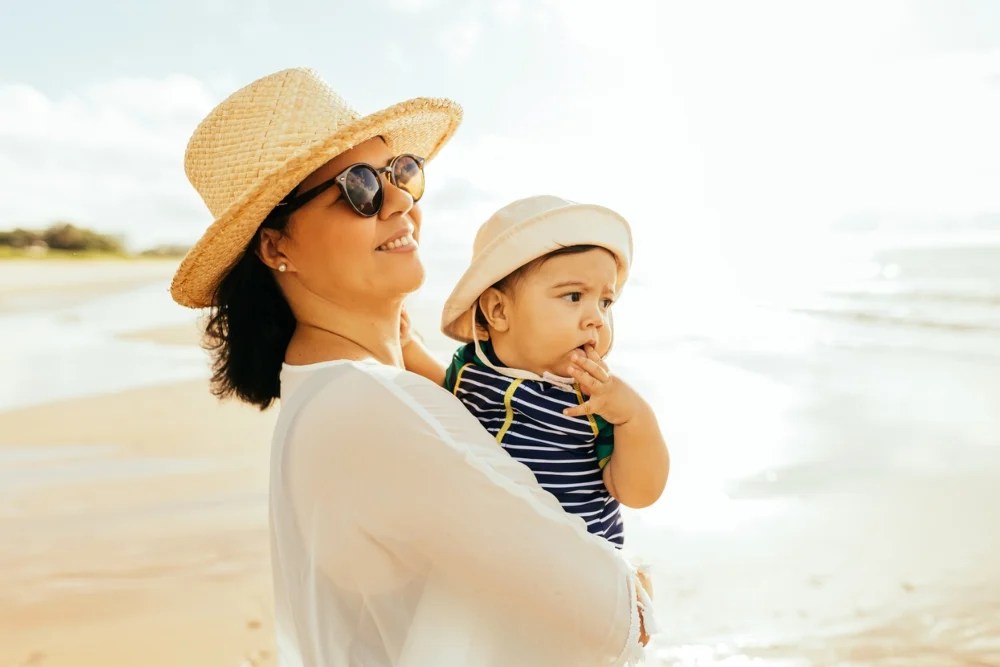 Madre con bebé en brazos disfrutando sus vacaciones en la playa