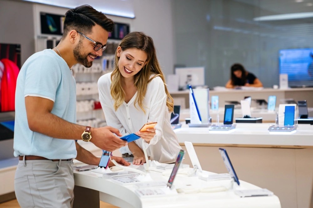metas de ahorro: persona con vendedor mostrandole un celular