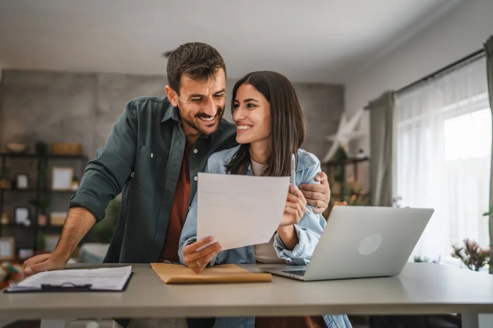 Pareja leyendo un documento sobre cómo refinanciar su crédito