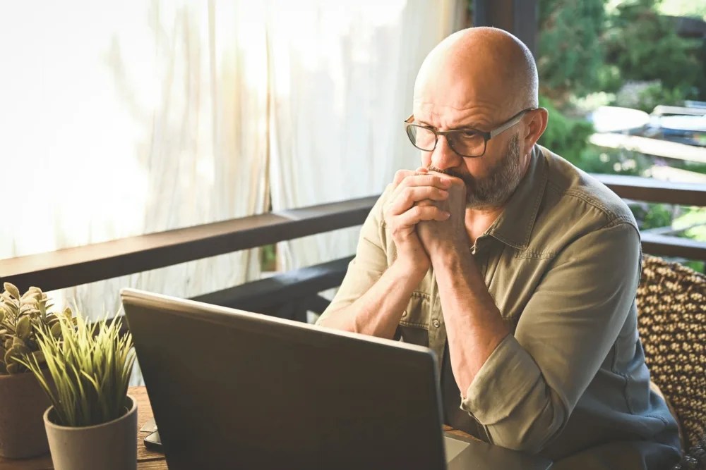 adulto mayor en computadora revisando que no haya sufrido un fraude