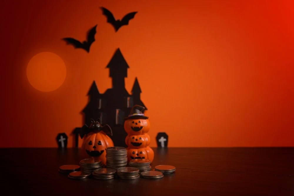 calabazas de halloween junto a monedas y un castillo de fondo