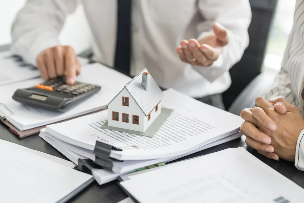 Personas con calculadora y papeles referente a compra de casa