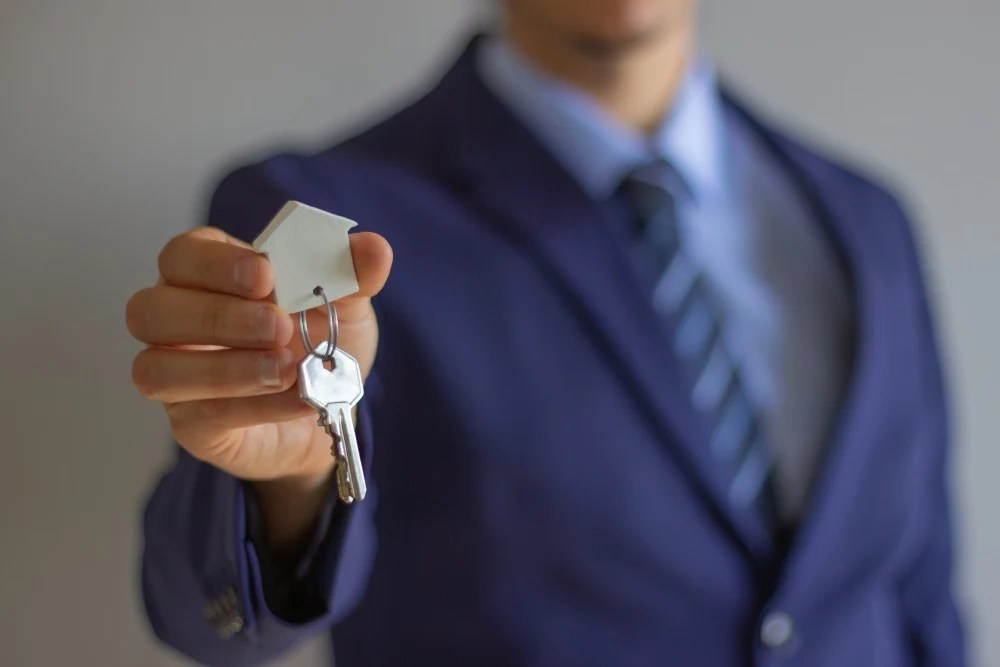 credito hipotecario: Hombre sosteniendo llavero con forma de casa,