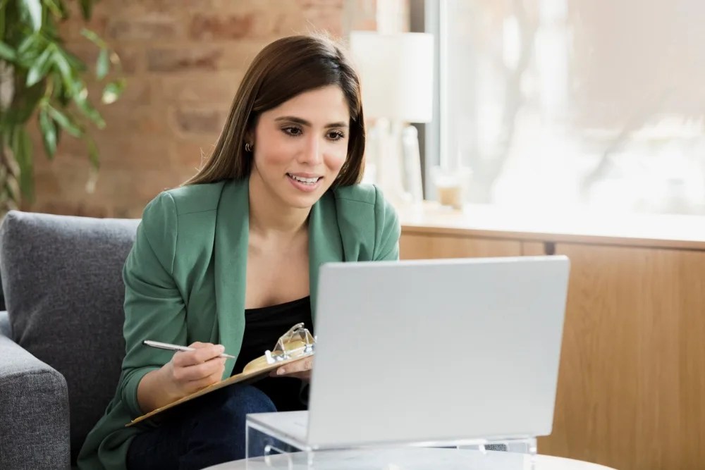 Mujer en computadora y tomando nota sobre los tipos de salario base