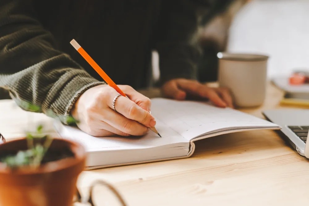 Persona escribiendo sus gastos para organizar según el método marie kondo