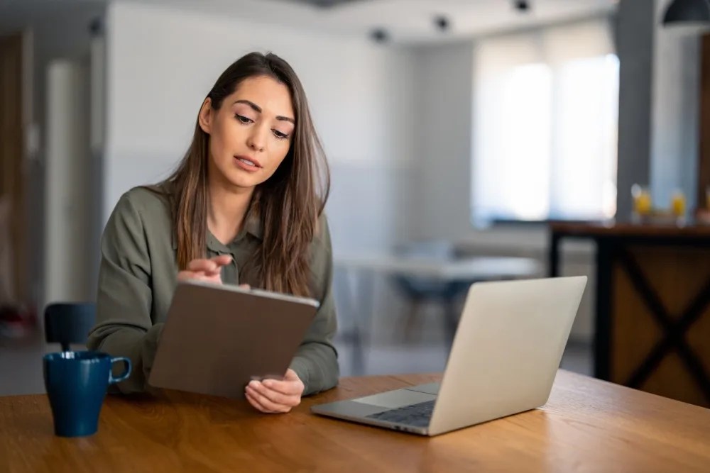 Mujer con computador y tablet revisando y organizando su presupuesto mensual personal