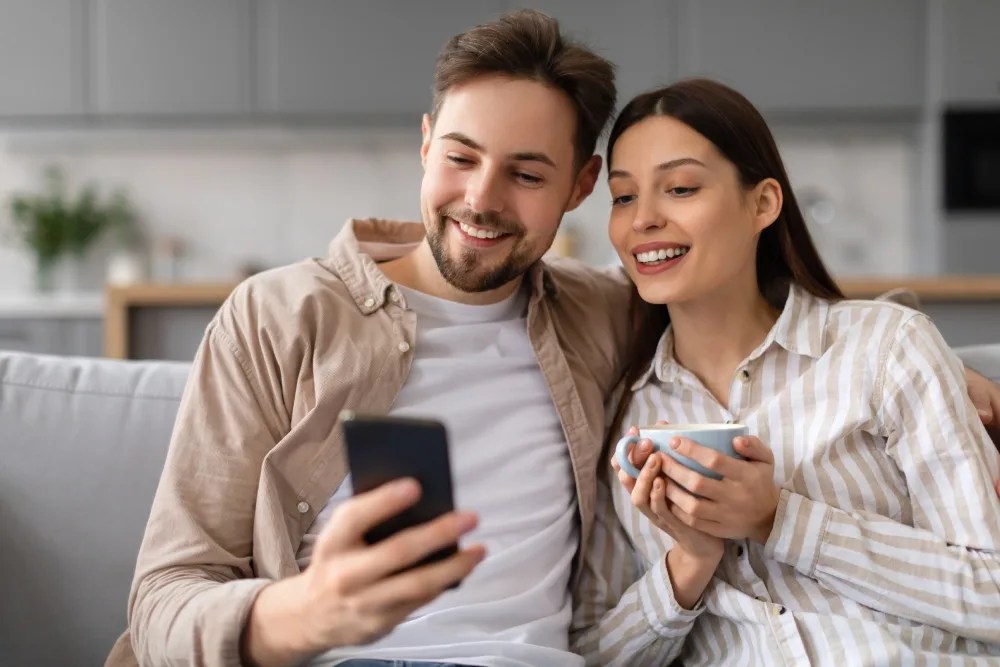 Pareja sentados en sofá revisando en celular qué es un plan financiero personal