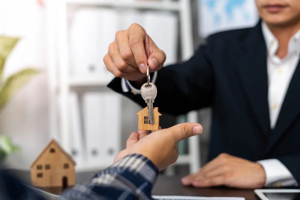 Agente hipotecario entregando las llaves de la casa al comprador