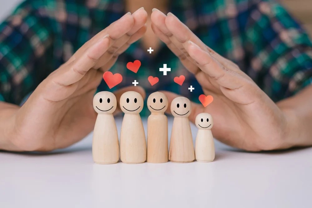 seguridad financiera: persona formando con sus manos una casa sobre familia de madera