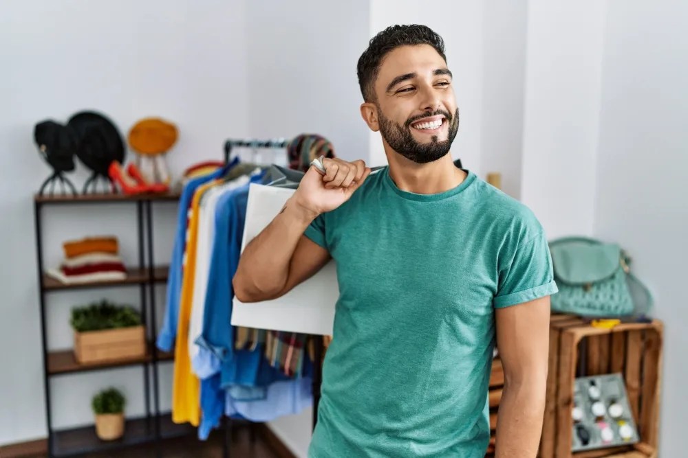 Hombre con pila de ropa que comprará