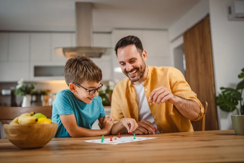 Padre enseñandole con un juego a hijo para aprender a ahorrar