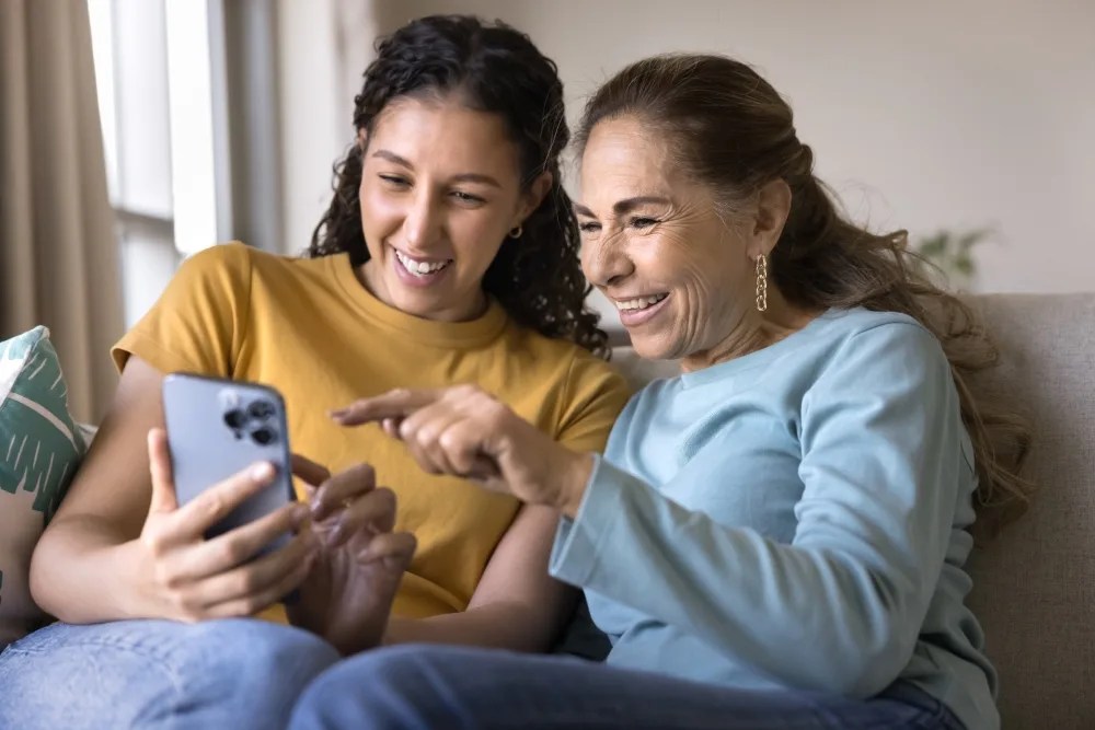 Madre e hija en celular enseñando a enviar dinero al extranjero