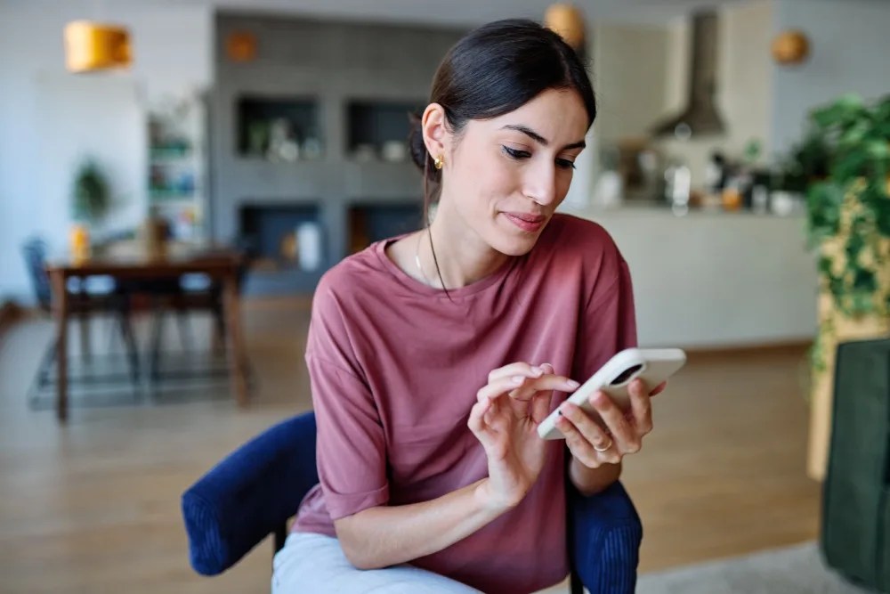 Mujer realizando en su celular envío de dinero al extranjero.