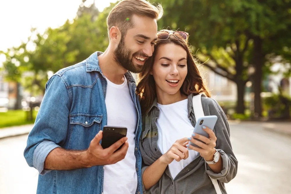 Pareja revisando celular para ver dónde invertir su dinero