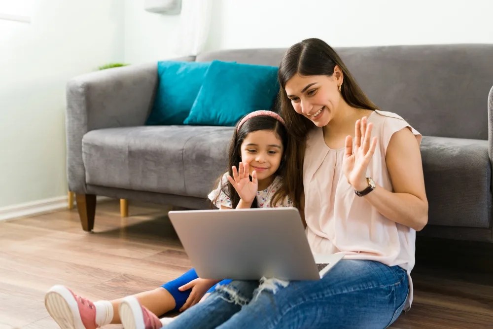 madre e hija saludando en computador luego de recibir remesas