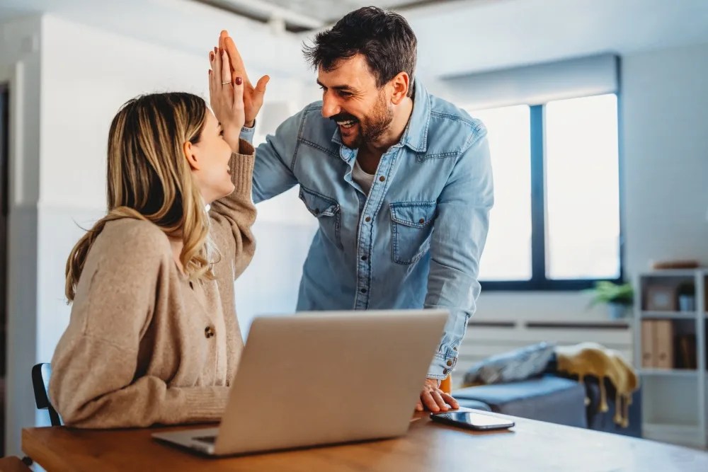pareja chocando los cinco al realizar pagos anticipados en crédito hipotecario