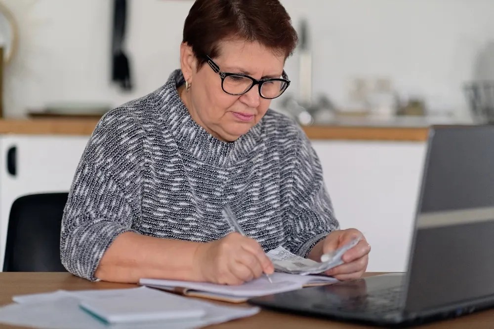 Adulta mayor tomando notas de tips para cuidar el dinero