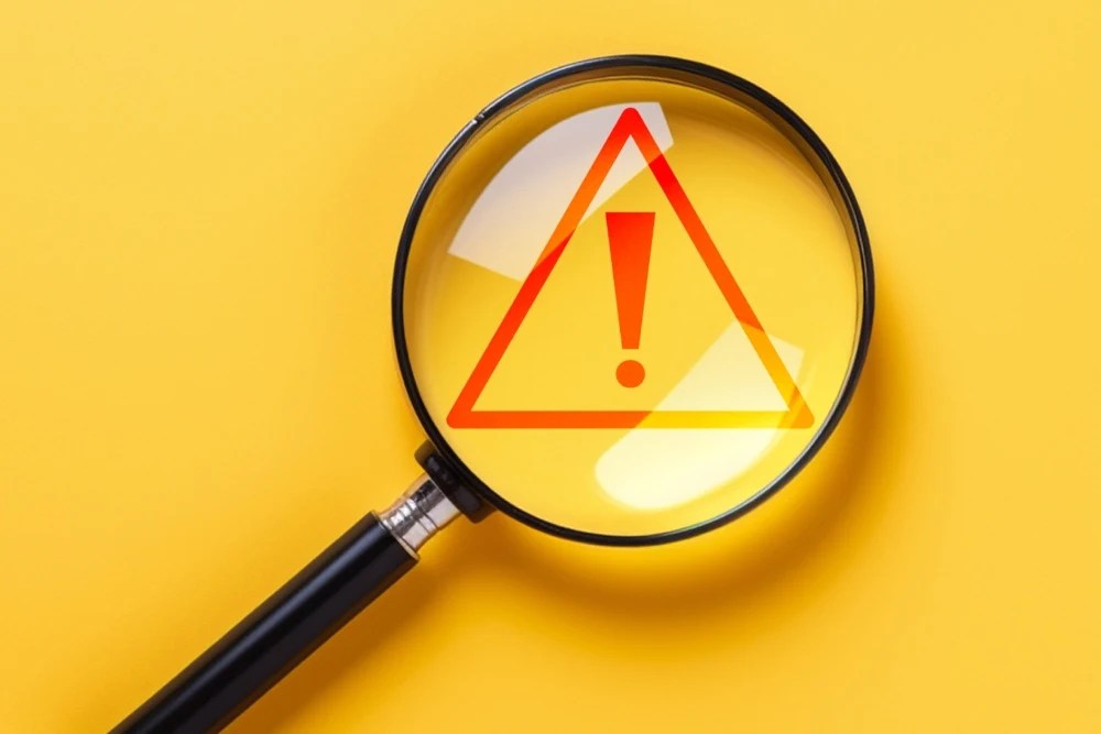 lupa y signo que advertencia representando los fraudes en créditos hipotecarios