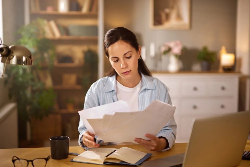 Mujer con documentos revisando su historial crediticio para optar por un crédito hipotecario