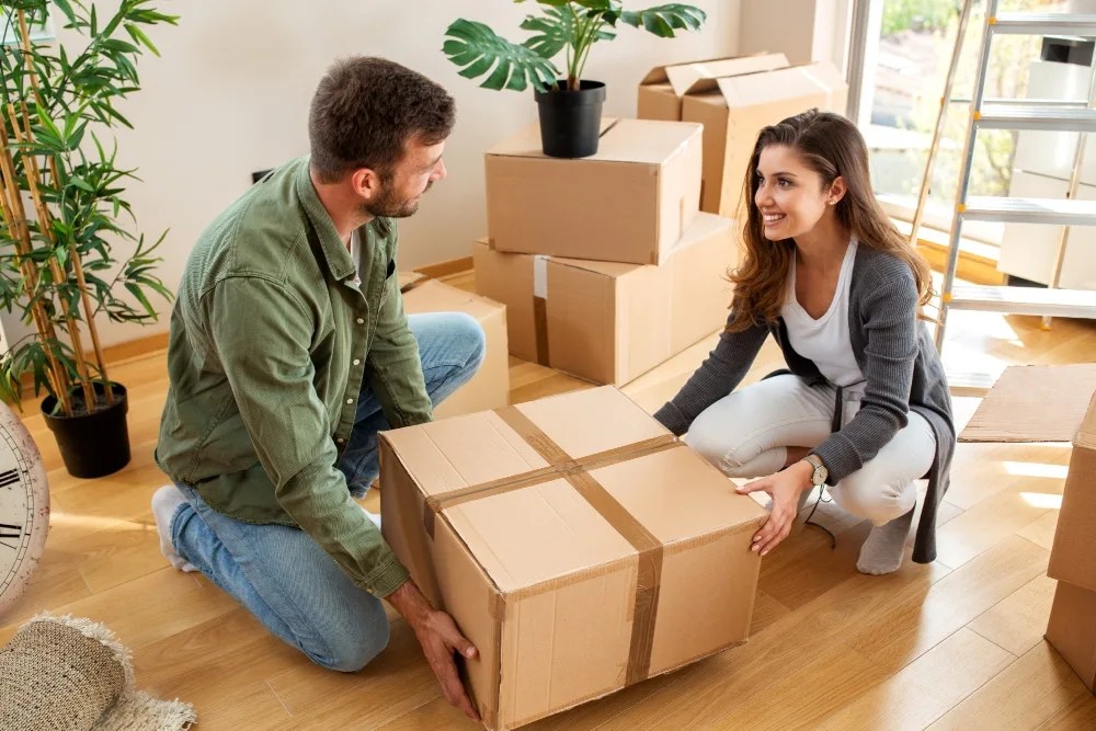 Pareja con cajas de mudanza al tener la capacidad de pago de su crédito hipotecario