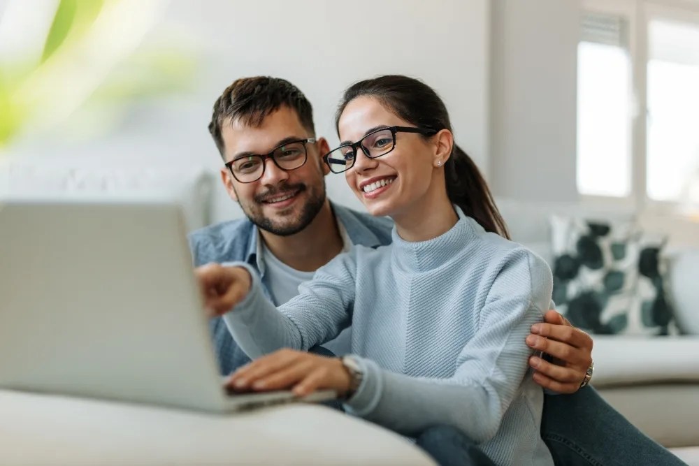 Pareja con computadora revisando tasa de interés de créditos hipotecarios